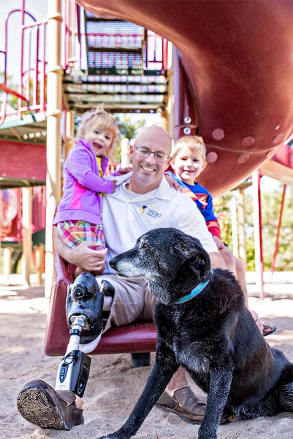 Ben Blecha sitting on slide with son, daughter, and dog