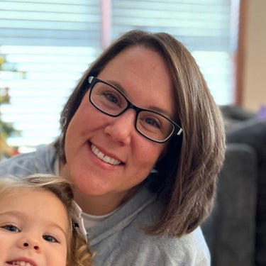 Dr. Michelle Beck with glasses and a child smiling indoors
